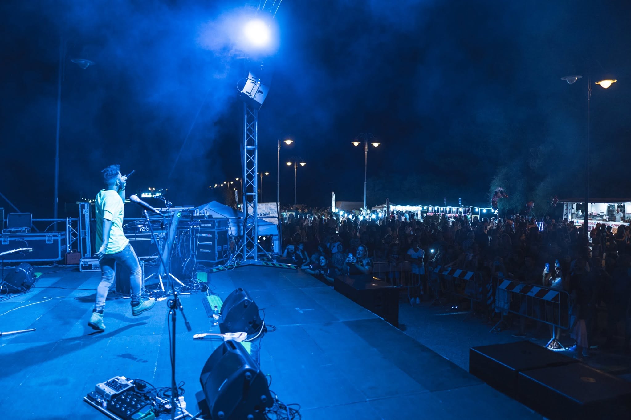 Stefano canta sul palco davanti al pubblico, sotto le luci blu