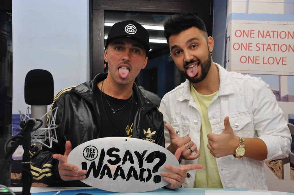 Stefano nello studio di Radio Deejay, davanti al microfono e al cartello Say Waaad?